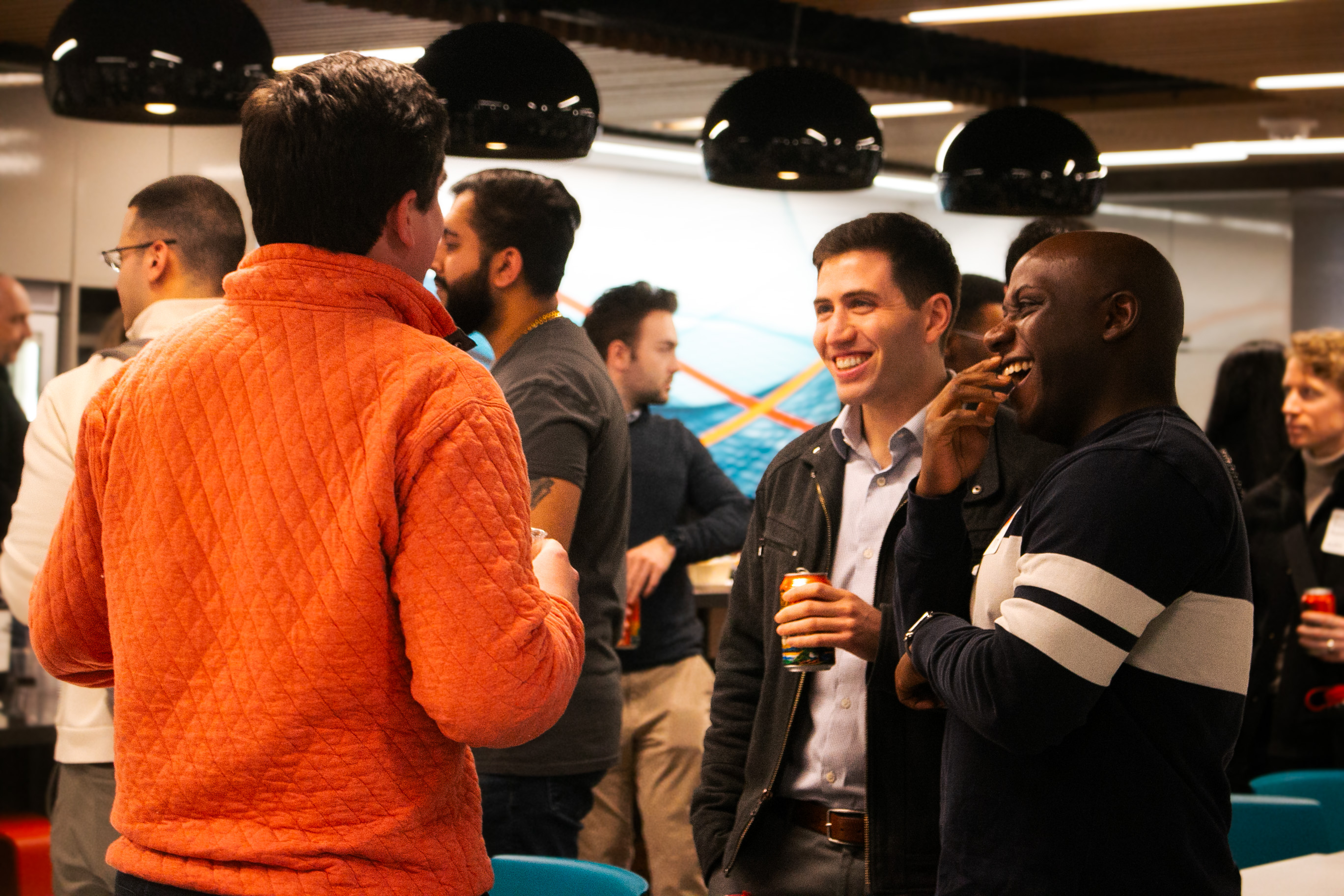 Three men are smiling and laughing in discussion with one another. 