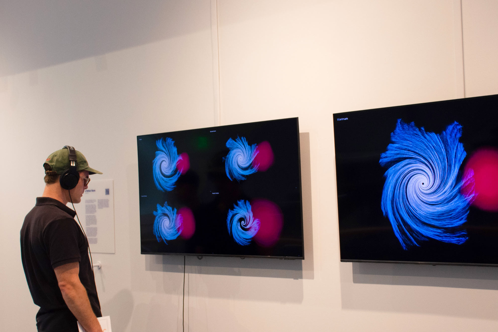 Man wearing headphones looking at two monitors with red and blue data shapes