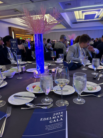 2024 Edelman Gala tabletop scene with program, dinnerware and decor