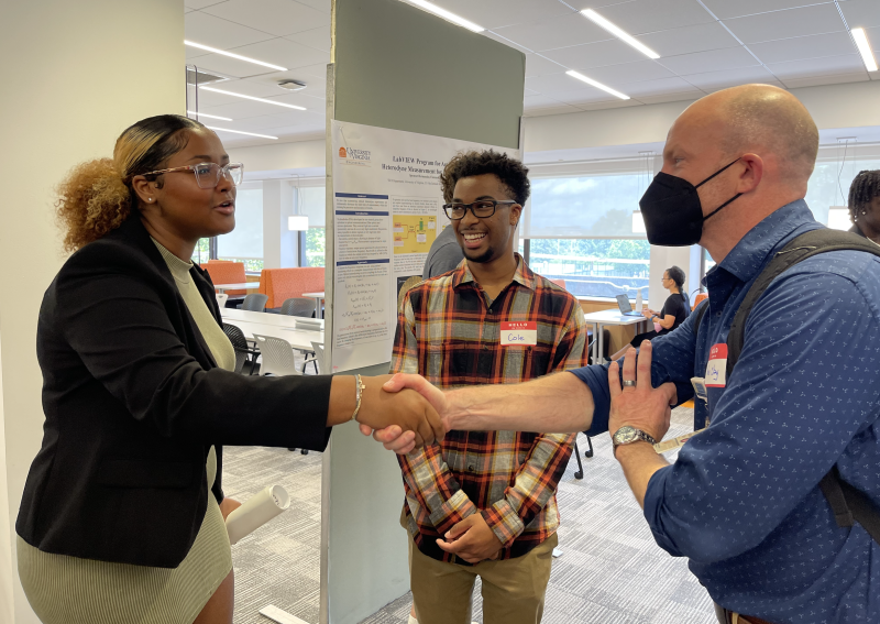 Cole and Joya shake hands with professor