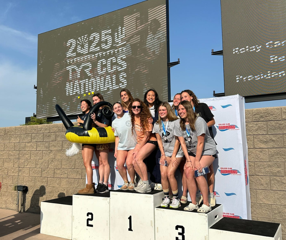 Elizabeth Miller poses with fellow swimmers on top of a podium.