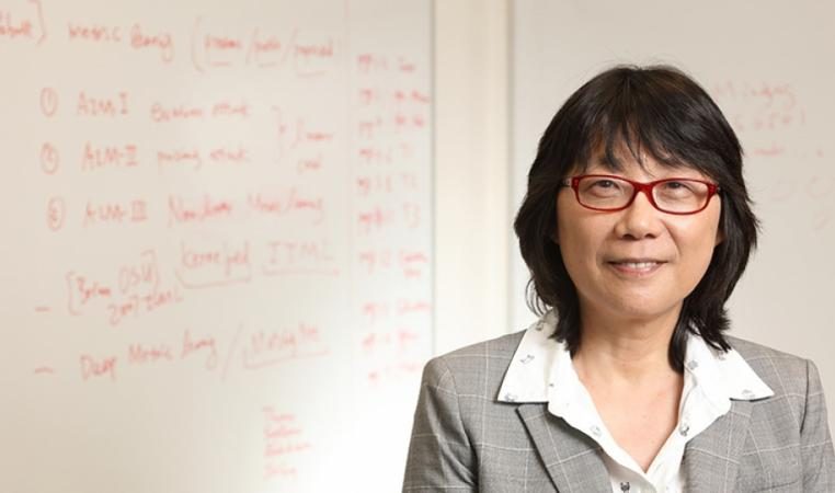 Aidong Zhang standing in front of a white board