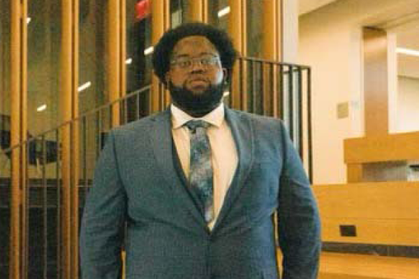 UVA Data Science MSDS student Didier Kasole in auditorium post-undergraduate in suit and tie