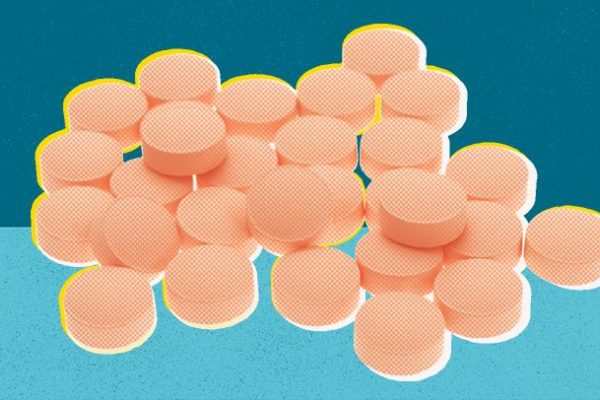 Illustration of a pile of orange pills on a blue textured surface. Pills have a dotted pattern and cast soft shadows.