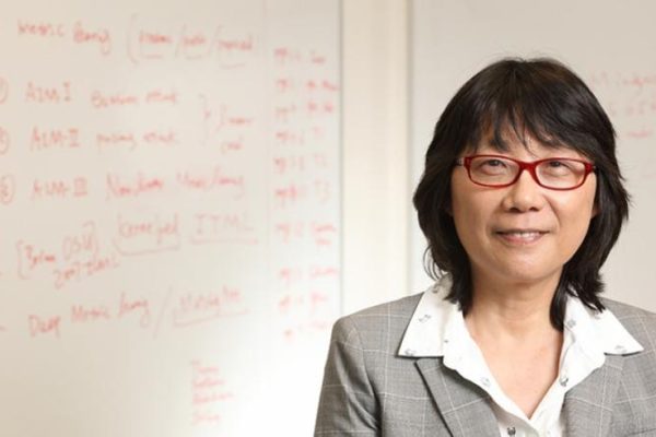 Aidong Zhang standing in front of a white board