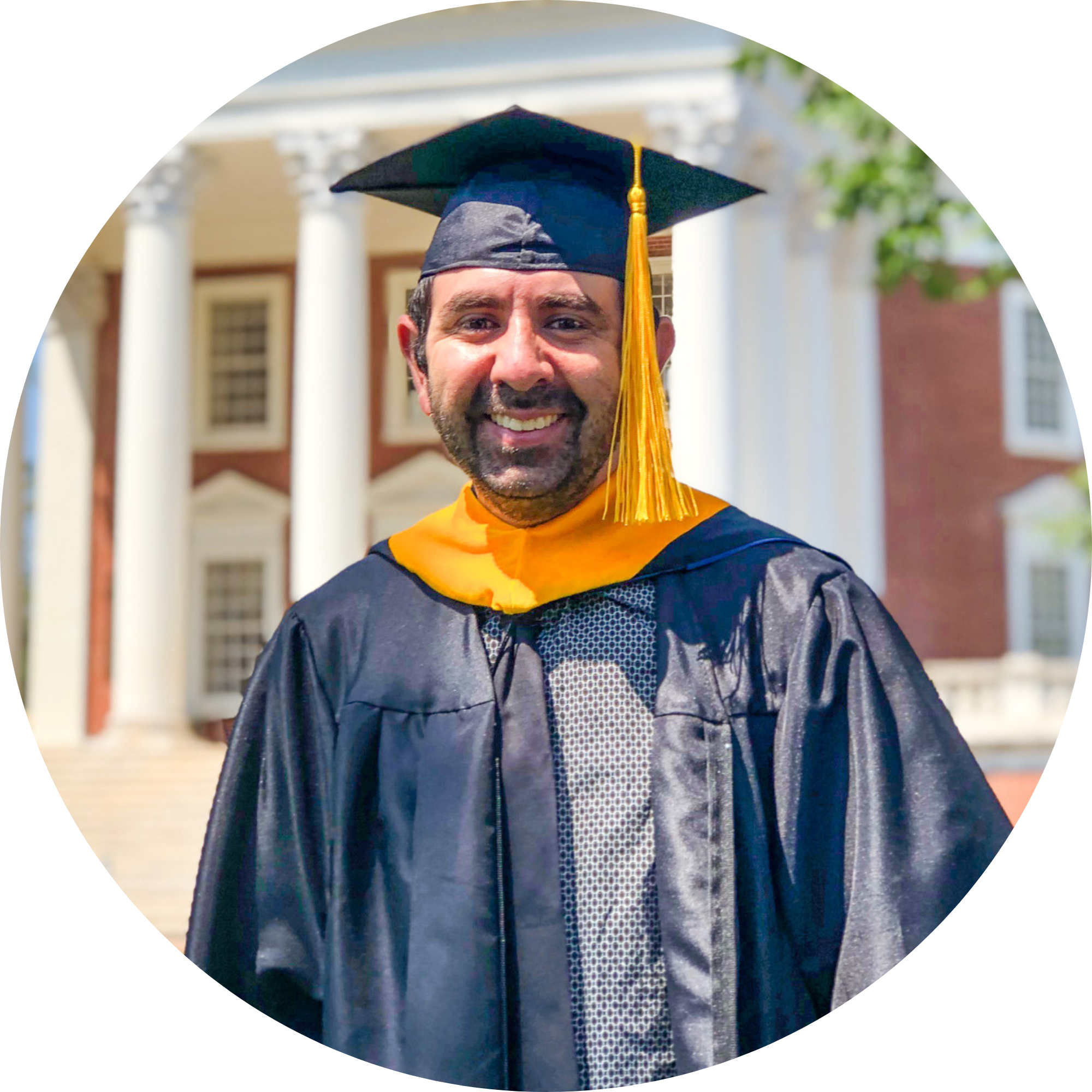 Travis wearing graduation attire smiling in front of the Rotunda.